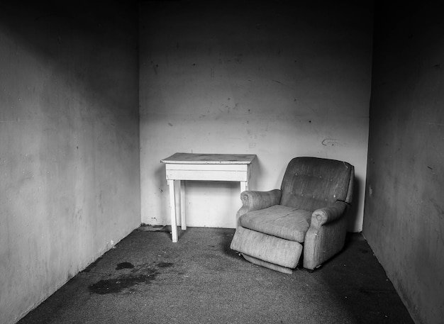 A black and white photograph of a living room after an alleged spontaneous human combustion event. The room appears relatively undamaged, except for a charred area on the floor where a person supposedly combusted. The contrast between the intact room and the localized damage is striking.